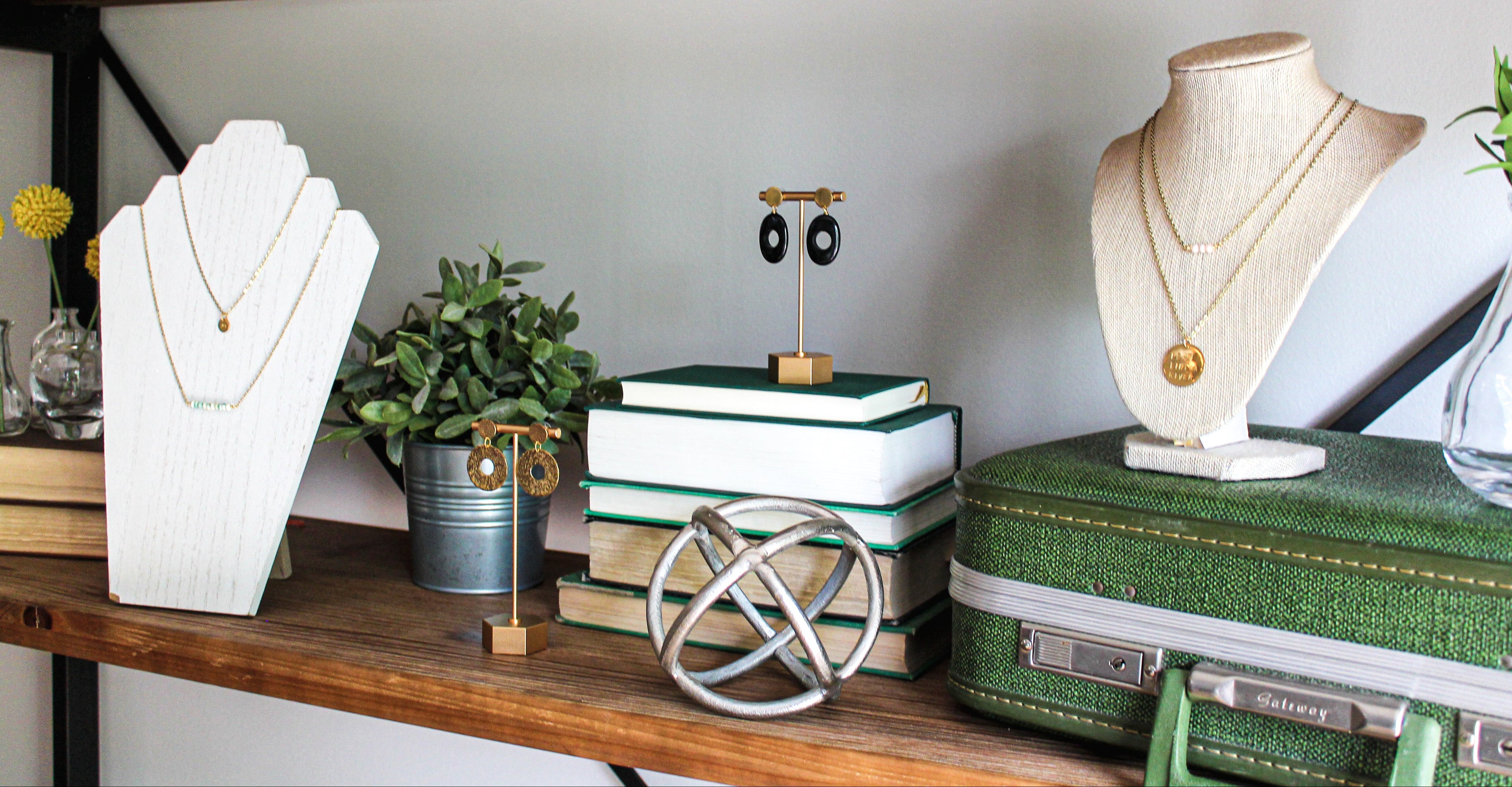 Jewelry display on a wooden shelf with books and decorative items.